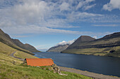 Cabin with a red roof by the fjord. Bordoy, Faroe Islands.