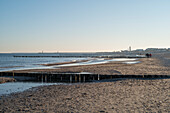 Am Ostseestrand von Warnemünde mit Blick auf den Leuchtturm, die Westmole und die Muschel am Morgen mit Touristen am Strand, Rostock, Mecklenburg-Vorpommern, Deutschland