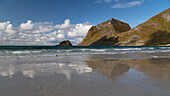 Mountains are reflected on the beach at Vik Beach, Lofoten, Norway.