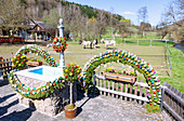 mit bunten Ostereiern geschmückter Osterbrunnen an der Leinleiter in Zoggendorf in der Fränkischen Schweiz, Bayern, Deutschland
