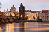 Karlsbrücke mit Altstädter Brückenturm, Kreuzherrenkirche, Lichtspuren eines Ausflugsschiffes auf der Moldau, Prag, Tschechien