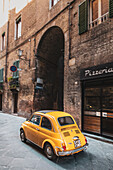 Old couple in vintage Fiat 500 in alley of old town, Siena, Tuscany, Italy, Europe