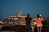 Menschen fotografieren Panorama auf Altstadt und Dom Santa Maria Assunta im Abendlicht, Siena, Toskana, Italien, Europa