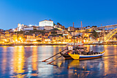 Barcos Rabelos, Portweinboote auf dem Fluss Duero vor der der Brücke Dom Luís I und der historischen Altstadt von Porto bei Nacht, Portugal