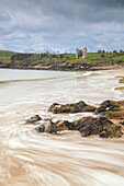 Minard Castle on Minard Strand. Traces of water on the rock in the foreground. County Kerry, Ireland.