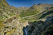 Woman hiking standing on slab of rock high above Reculaz Gorge, Vanoise National Park, Vanoise, Savoie, France