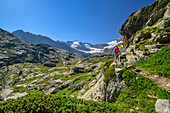 Man and woman hiking descending from Refuge des Evettes, Vanoise National Park, Vanoise, Savoy, France