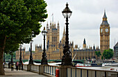Die Houses of Parliament von der Southbank, London an einem bewölkten Tag, mit alten Laternenpfählen im Vordergrund