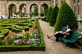 Paar sitzt auf einer Bank in den Gärten des Musée Carnavalet, Marais, Paris, Frankreich