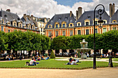 People sitting in the park at Place des Vosges, The Marais, Paris, France