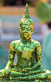 Buddha statue with gold leaf flaking at the Grand Palace Bangkok, Thailand