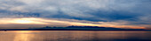 Wide angle view of Puget Sound with Olympic mountain range beyond and cloudy sky, USA