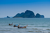Lange Boote machten vor dem Strand in Ao Nang mit der Insel dahinter fest, Thailand