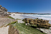 Rock formations and cliffs overlooking a sandy beach with waves breaking on shore, Walker Bay Nature Reserve, South Africa