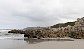 The jagged rocks and coastline of the Atlantic coast at Grotto Beach, a wide beach near Hermanus, South Africa