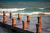 A wooden pier with posts or bollards on the coastline
