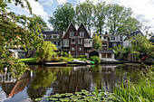 Characteristic apartment buildings at Schellingwouderdijk, boats, water lilies, Amsterdam, North Holland, Netherlands