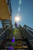Woman Walking Down on a Staircase with Sunbeam and Lens Flare in Lugano, Ticino, Switzerland.