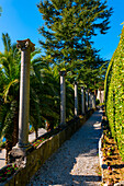 Gehweg mit Säule und Palme an einem sonnigen Tag mit klarem Himmel in Lugano, Tessin, Schweiz.
