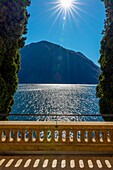 Balkon Blick über den Luganersee mit Baum und Berg an einem sonnigen Tag in Lugano, Tessin, Schweiz.