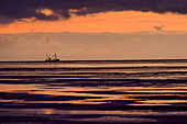 Ship sailing off Westerhever at dusk, Westerheversand, Westerhever, Wadden Sea National Park, Schleswig-Holstein, Germany