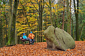 Mann und Frau beim Wandern machen Rast am Karlstein, Heidschnuckenweg, Naturschutzgebiet Buchenwälder im Rosengarten, Staatsforst Rosengarten, Niedersachsen, Deutschland