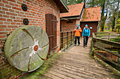 Man and woman hike past the mill on the Örtze, Örtze, Müden, Heidschnuckenweg, Lower Saxony, Germany