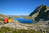 Man and woman hiking sitting at Wildkarsee, Wildkarsee, Hohe Tauern National Park, Zillertal Alps, Salzburg, Austria