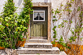 Eine alte Eingangstüre zu einem idyllischen Haus aus Stein in der historischen Altstadt von Obidos, Portugal