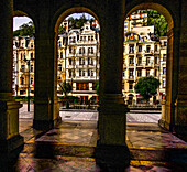 Blick durch die Arkaden der Mühlbrunnen-Kolonnade zu den historischen Gebäuden an der Kreuzgasse (Vridelni), Karlsbad, Karlovy Vary, Tschechische Republik