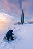St. Petersburg,. Russland - 27. Januar 2019. Wolkenkratzer Lakhta Center (Gazprom-Zentrale) in der Dämmerung. Fischer in einem zugefrorenen Meer während des Sonnenuntergangs.