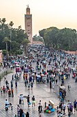 Koutoubia Mosque rises above the crowded Jemaa el-Fnaa square below at dusk,Marrekech,Morocco.