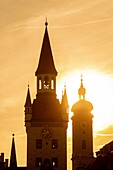 Die Sonne geht auf den Glockentürmen in der Altstadt Marienplatz in München unter.