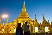Myanmar (früher Burma). Rangun. (Rangoon). Die buddhistische Shwedagon-Pagode ist das erste religiöse Zentrum Burmas, da sie der Legende nach Relikte von vier alten Buddhas enthält, darunter acht Haare des Gautama-Buddha. Menschen vor dem großen goldenen Stupa.
