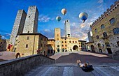 Heißluftballons über der Piazza Duomo (Domplatz) von San Gimignano mit ihren mittelalterlichen Türmen, die als Verteidigungstürme gebaut wurden, aber auch, um den Reichtum der Familie durch die Höhe der Türme anzuzeigen. Eine UNESCO-Weltkulturerbestätte. San Gimignano; Toskana Italien.