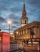 Westminster, London - St. Martin-in-the-Fields Church und rote Telefonzellen, die vom Ausgang Strand der U-Bahnstation Charing Cross aufgenommen wurden.