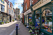 Blick auf Geschäfte und Cafés auf Kirkgate und die Kathedrale im Hintergrund, Ripon, North Yorkshire, England, Vereinigtes Königreich, Europa