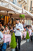 Kellner serviert am Tisch im Restaurant im Freien, Piazza Navona, Rom, Latium, Italien, Europa