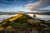 A man looking across The Great Ridge during a cloud inversion with view of Mam Tor, Hope Valley, Peak District, Derbyshire, England, United Kingdom, Europe