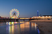Big wheel and amusements on Central Pier at sunset with Blackpool Tower, Blackpool, Lancashire, England, United Kingdom, Europe