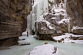 A male wearing red coat stood in Maligne Canyon during winter conditions, Jasper National Park, UNESCO World Heritage Site, Alberta, Canada, North America