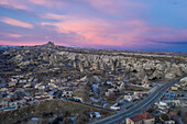 Turkey, Cappadocia, Aerial view of rock formations and village at dusk