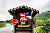 USA, Alaska, American flag and stop sign on cabin