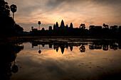 Cambodia, Siem Reap, Silhouette of Angkor Wat seen across water at sunrise