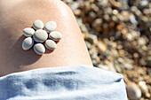 Pebbles arranged in flower shape on girls (4-5) leg