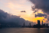 Blick auf die Skyline von Hongkong mit Victoria Harbour unter den Gewitterwolken in Hongkong, China