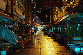 View of street and half-closed market stall at night in Hong Kong