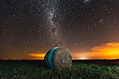 Malerischer Blick auf Heuballen auf landwirtschaftlichen Feldern gegen die Milchstraße im Himmel