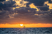 USA, Florida, Boca Raton, Sonnenaufgang über dem Meer mit Silhouette des Segelboots in der Ferne