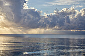 Wolken und Sonnenstrahlen über dem Meer bei Sonnenaufgang
